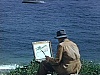 Peintre aquarelliste assis et au travail au bord de la plage en Gaspésie