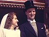 Mariage en queues de pie, haut de forme, robes à traîne et canne avec des militaires et des guides à la sortie de l'église