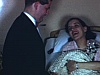 La mère au lit, à l'hôpital, reçoit la visite de tous pour le baptême qui a eu lieu sans elle.  Plusieurs femmes à chapeaux; on prend un verre et on trinque.