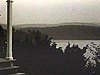 Paysage sur lac, grands-parents devant la maison, grand quai sur le lac; arbres, forêt et madame en pantalons golf