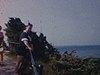 Bord de mer, homme avec appareil photo au bord de la mer; des baigneurs et flâneurs sur la plage
