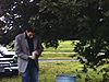 A la campagne, un homme vient d'arriver en automobile sort une cannette d'une poubelle qui fait une glacière et débouche avec l'ouvre-bouteille accroché à la poubelle, boit quelques gorgées et se dirigent vers le feu de camp
