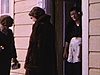 Dame en manteau de fourrure avec sa valise qui attend l'autobus (devant station-service Esso) pour Québec; l'autobus arrive (départ)