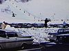 Embouteillage au centre de ski. Un homme sort ses skis de la valise de l'automobile, les cire et part avec ses skis sur l'épaule