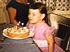 Anniversaire de fillette, elle nous montre ses cadeaux: poupée géante, ski, elle souffle ses bougies sur son gâteau, famille à la cuisine