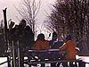 Les skieurs du mont Royal assis autour d'une table à pique-nique pour la pause (un enfant couché dans la neige à leurs côtés)