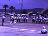 Spectacle de fanfare dans un petit stade (Lakewood, Floride?); palmiers et drapeaux US