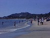 Plan sur la plage (Acapulco?) ; baigneurs et deux militaires qui circulent armes à la main