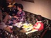 Noël 70's; on déballe des cadeaux de sous l'arbre; aspirateur en cadeau; paquets de papiers d'emballage qui jonchent le plancher