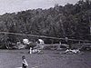 Courses de canots sur un lac; voilier sur le lac et arrivée de deux gros Rabaska (gros canots)