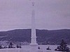 Prêtre et adultes près d'un monument; vieille pièce d'artillerie abandonnée (guerre)