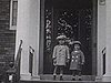 Années 20; enfants qui descendent l'escalier de l'entrée  de la maison, puis, debouts sur la malle arrière de l'automobile