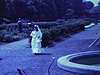 Une jolie première communiante en costume dans un jardin botanique qui pose et se promène (bye-bye à la caméra) avec sa famille (3 générations)