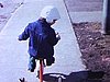 Petite fille en tricycle sur le trottoir en ville; beau plan: elle sourit à la caméra