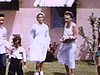 La famille avec les enfants devant le motel; grand-mère donne des cadeaux et ils exhibent leurs cadeaux; petite haie de fleurs (Floride)