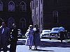 Groupe devant un espèce de couvent; plusieurs personnes, automobiles, etc.