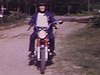 Adolescent à moto, puis petit groupe d'adolescents font des acrobaties