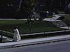 Homme en soutane (frère missionnaire?) se promène devant l'église, pose avec enfants et aide un petit garçon à réparer son tricycle, s'embrasse