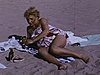 Années 50, madame se fait bronzer sur la plage, les enfants jouent dans les vagues et dans le sable