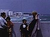Années 50: famille dans le sud, sur le bord de l'eau, pêcheurs sur le quai, enfants  assis à l'ombre sous un petit arbre