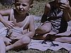 Enfant assis par terre, l'été à l'extérieur, un garçon tient un poussin et le montre à la caméra (beau plan)