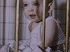 Bébé dans bassinette se tient après les barreaux.