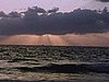 Beau coucher de soleil sur la mer: rayons du soleil derrière les nuages