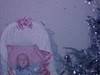 Bébé au salon, dans un panier, à côté de l'arbre de Noël argenté, famille assise sur le sofa, les adultes discutent