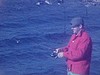Un pêcheur au bord de l'eau, pêche une truite