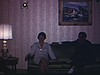 Madame et monsieur sur le divan du salon discutent avec un religieux (frère). Religieux discute avec deux hommes dont un prêtre