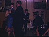 Une dame danse avec un prêtre. ils tiennent un appareil photo à la main en dansant et se prennent en photo. Le prêtre cruise un peu. Danse au sous-sol