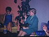 Réunion de femmes au salon: membres d'un club de tricot (club social spontané), elles jasent et boivent un verre mais ne tricotent pas. Les maris sont là aussi