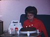Anniversaire d'une fillette de 6 ans: elle souffle avec difficulté ses bougies, près d'elle sa trousse de médecin reçue en cadeau et un plat avec une petite tortue) Elle rit, devant une petite table.