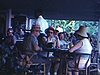 Groupe de touristes mangent sur une terrasse au Virgin Isles Hilton dans les Antilles; ils discutent devant l'hôtel, quelques plans urbains suivent