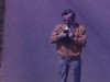Monsieur debout au milieu de la route prend une photo en pointant l'appareil vers nous