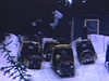Cinq motoneiges stationées près du chalet refuge. Motoneigistes rejoignent leurs véhicules en saluant la caméra