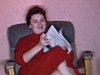 Madame au salon, s'assoit sur un fauteuil, lit le journal et va monter le son de la télévision qui est allumée