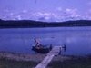 Chalet, bord de lac, enfants dans une chaloupe acostée au qui, maman les surveille, papa répare l'auto, vues du chalet et du lac