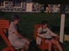 Motel, adultes se prélassent au soleil sur des chaises adirondack orange au bord de la piscine, motel et baigneurs, zoom-in sur drapeau du Québec