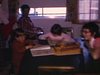 Enfants à la cuisine font des devoirs pendant que la mère fait à manger, jeune adolescente et enfants s'amusent avec des petites autos