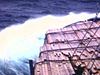 Navire en mer agitée. Sur le bateau, plein de bois d'oeuvre cordé et attaché. Radar en marche, divers plans sur le pont