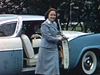 Deux jeunes femmes bien habillées qui sortent d'une automobile américaine 1950 bleue. Hument les lilas. Sourient à la caméra. Le marin sourit à la caméra