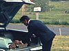Homme débouche une bouteille de bière avec un marteau qu'il prend dans le coffre de son automobile - boisson - alcool