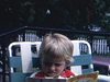 Beau plan d'une fillette qui lit, assise sur une chaise de jardin le livre «Black Sambo», puis elle sourit et grimace à la caméra