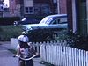 Sur le trottoir en ville, fillette en tricycle roule à reculons