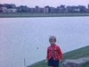 Fillette au bord d'un plan d'eau. Pont au dessus d'un ruisseau dans un parc: fillette regarde sous le pont