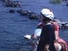 Fillette, bébé fille et mère assises sur une roche sur la rive d'une rivière