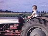 Fillette conduit un tracteur pendant que le fermier place son foin sur la plate-forme, la vache suit. Plusieurs beaux plans - charrette