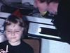 Fête d'enfant, Maman embrasse fillette qui embrasse bébé fille qui a un chapeau pointu. Papa embrasse fillette sur la bouche - baisers