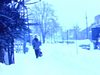 Plan de ville enneigée avec circulation. Mère promène sa fillette en traineau sur le trottoir. Père et fillette marchent sur trottoir en pleine tempête de neige, rue, autobus